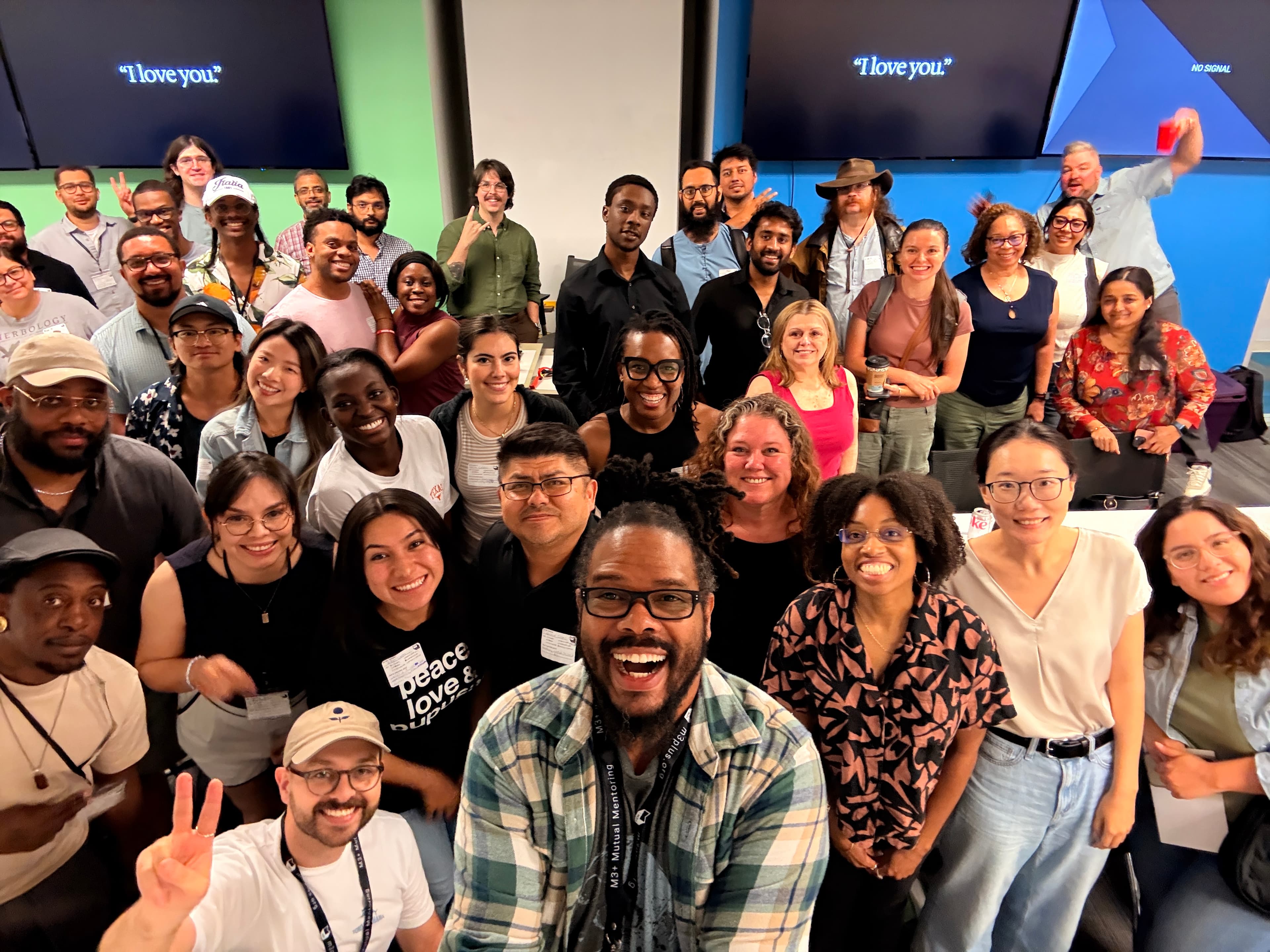 Big group selfie at an M3+ meetup with name badges everywhere